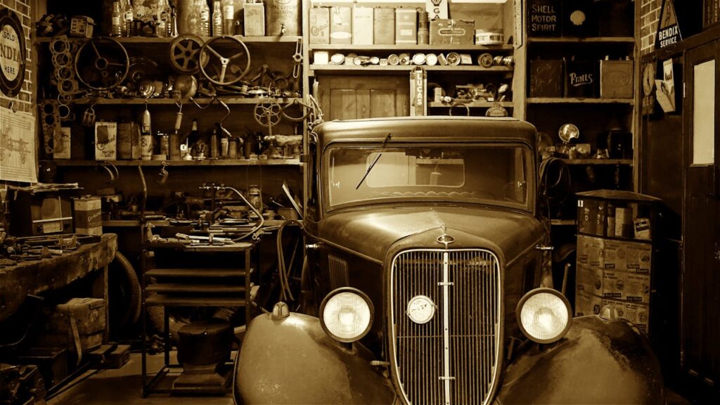 A vintage car surrounded by antique tools and parts in a nostalgic workshop.